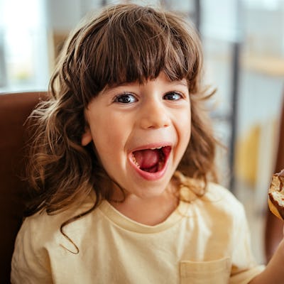 Boy is sitting at the table and eating a donut for breakfast — a new study looked at how many calories kids get from ultra-processed foods.