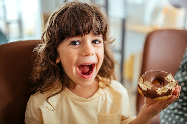 Boy is sitting at the table and eating a donut for breakfast — a new study looked at how many calori...