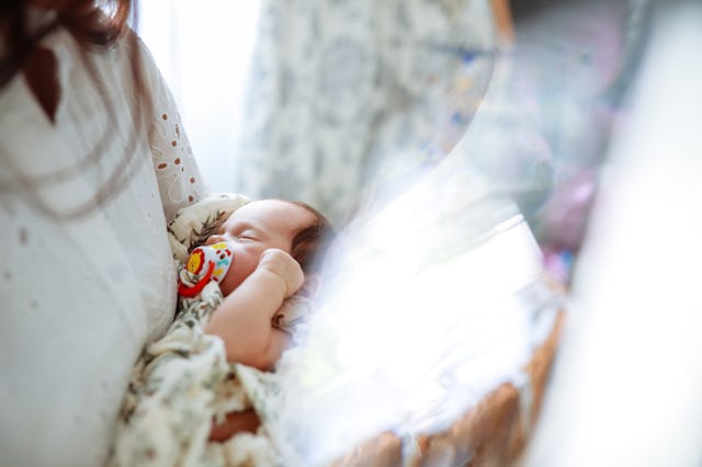 sleeping newborn girl in mother's arms, close-up shot
