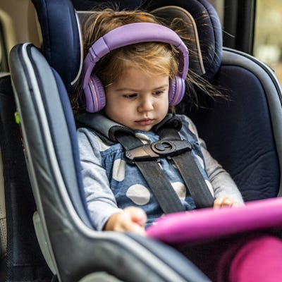 Young girl using digital tablet in back of car