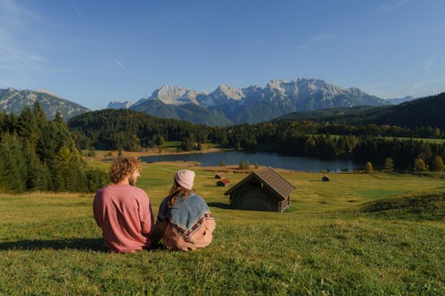 Man and woman sitting on the meadow near Geroldsee in Bavarian Alps, Germany in autumn and looking a...