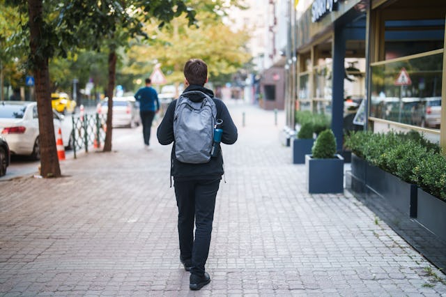 Back view of a male high school student walking on a pedestrian walkway.