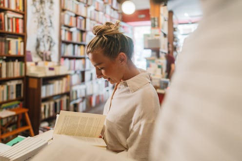 Photo of a mid adult woman, scrolling the books and looking for the favorite author and tittle in a ...
