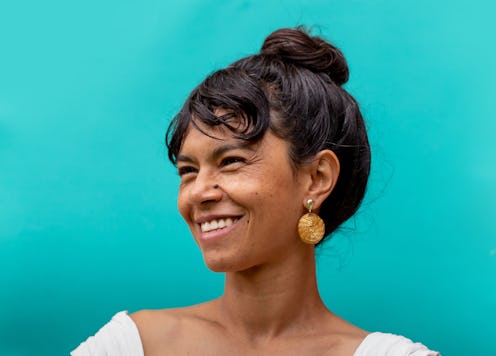 Hispanic woman with toothy smile on teal background