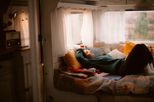 Young woman lying with eyes closed in the bed in camper trailer