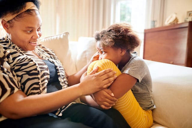 Mother consoling her sad daughter while sitting on sofa at home, in a story about what to do when yo...