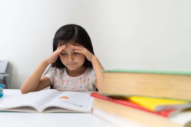 A little girl reading a book in class with her hands on her forehead. We chat about the worst childr...