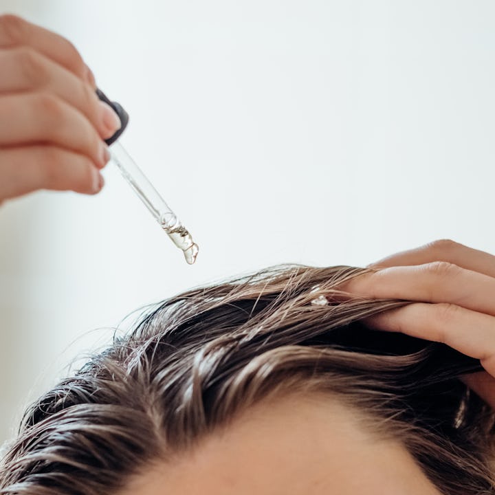 Woman applies oil to her hair with pipette, in a story about what supplements help with hair loss