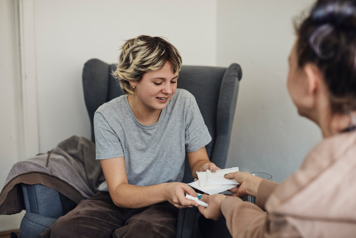 School nurse hands pads and a tampon to a student, in a story answering the question Is it normal to be irregular after your first period?