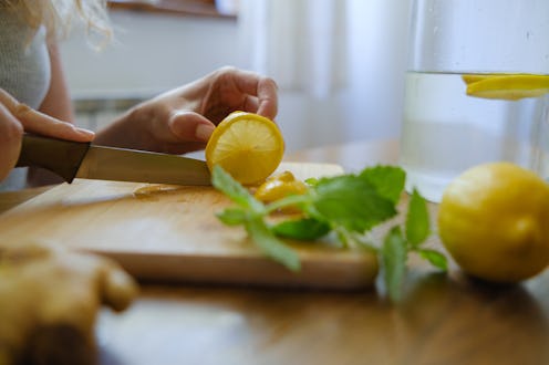 woman cutting lemon at kitchen table at home
