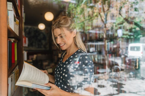 Photo of a mid adult woman, scrolling the books and looking for the favorite author and tittle in a ...