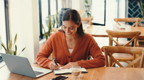 Business, woman and laptop with writing in cafe with paperwork, remote work and copywriting with not...