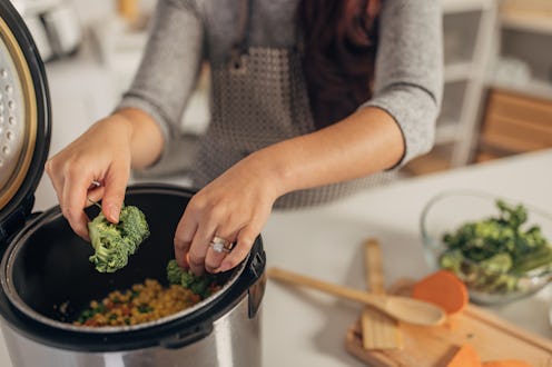 Hispanic woman using slow cooker while preparing food in the kitchen