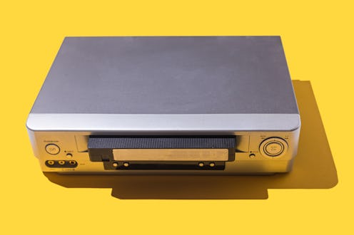 VHS video player with a tape half inserted, on a yellow background. Image concept, retro, audiovisua...