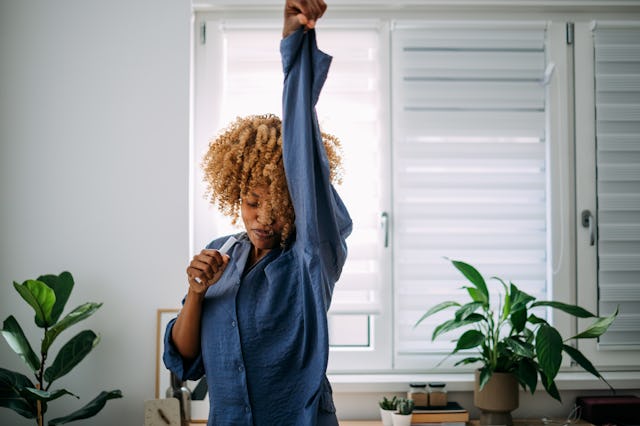 Cheerful African American woman in pajamas singing and dancing in the morning.