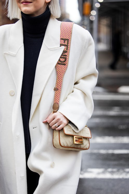 NEW YORK, NEW YORK - FEBRUARY 13: A guest wears oversized white coat, Fendi bag outside Michael Kors...