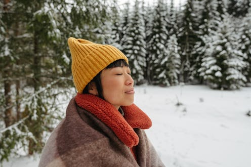 Photo of an Asian woman camping out in a tent, enjoys beautiful nature covered in snow