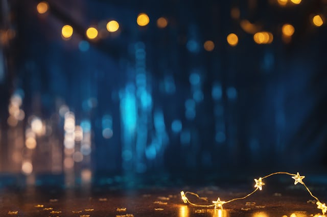 New Year or Christmas celebration concept with defocused golden lights on navy blue tinsel backgroun...