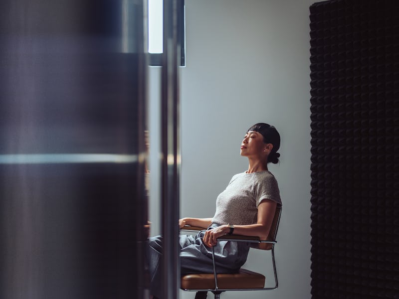 Businesswoman sitting with eyes closed, taking a break in a modern office. Concept of relaxation, st...