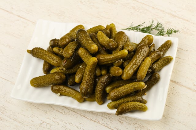 Picled cucumbers in the bowl over wooden background