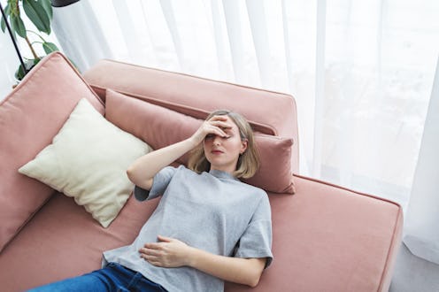 Mid adult woman in depression lying down on sofa