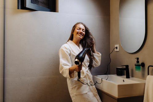 Shot of an attractive young woman blow drying her hair in the bathroom