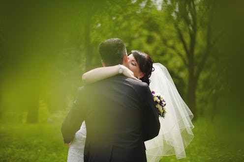 The bride and groom hug and kiss on their wedding day in the summer in the park
