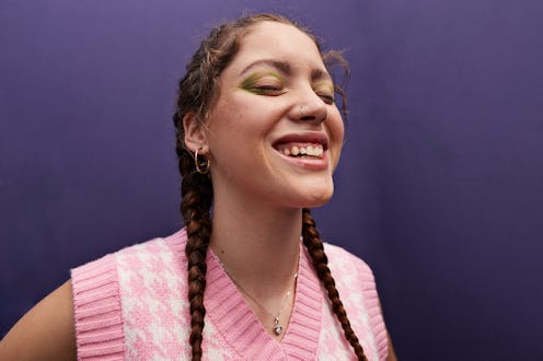 Happy woman with eyes closed against purple background