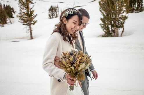 A young and attractive Asian woman and caucasian man get married in the mountains with snow from the...