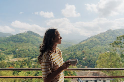 Woman drinking tea looking at tea plantation in Sri Lanka during her vacation