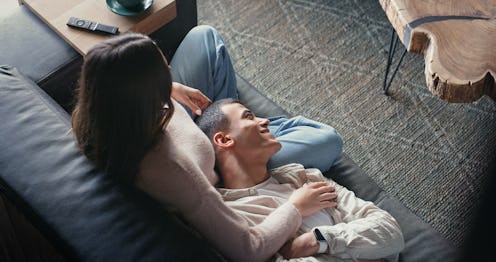 Above, house and couple on sofa, watching tv and relationship with love, care and comfort in living ...