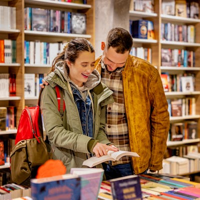 A young man and woman are checking out the latest literary offerings at a trendy book store, excited to discover their next favorite book