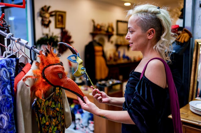 A woman explores a selection of unique and colorful vintage items in a second-hand store. She examin...