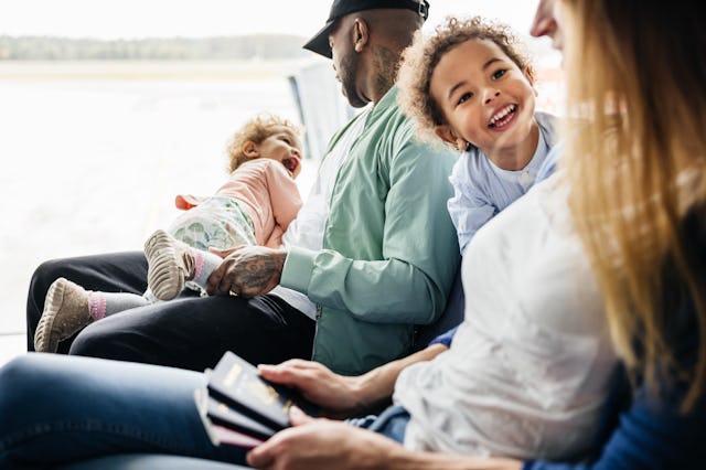A family shares a lighthearted moment in the airport seating area, with a child's laughter setting t...