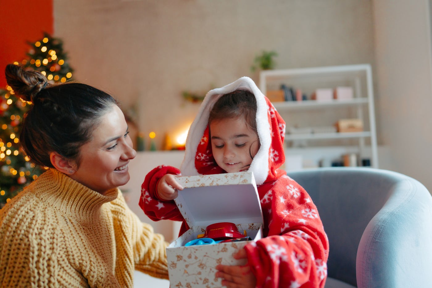 A mother and daughter during the Christmas holidays opening presents together.