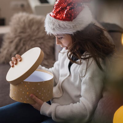 Happy young girl smiling when opening a gift box she got for Christmas