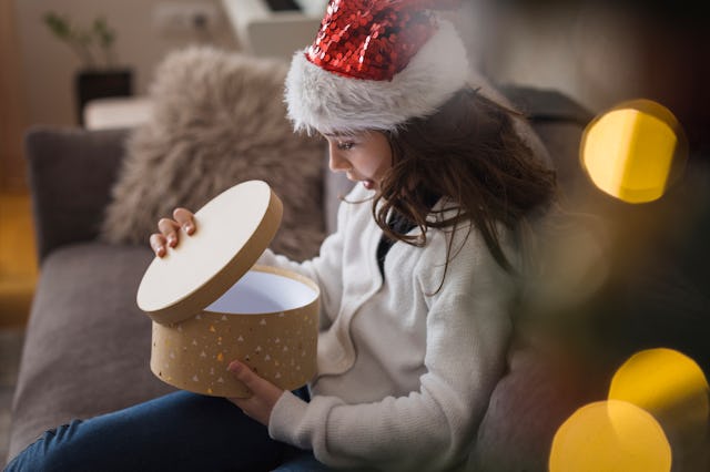 Happy young girl smiling when opening a gift box she got for Christmas