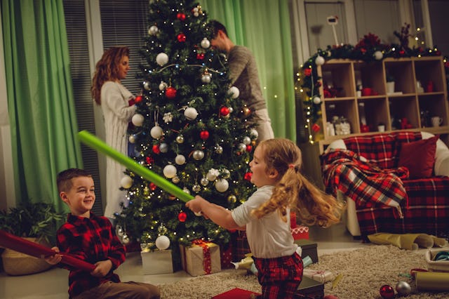 Candid shot of two little kids having fun playing with wrapping paper rolls they are using as swords...