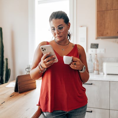 coffee break at home in the kitchen reading the smartphone