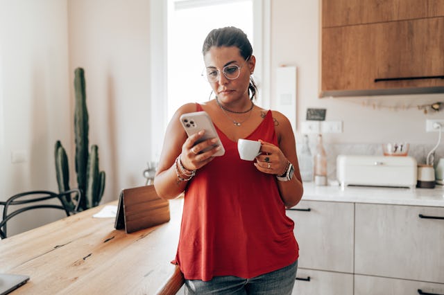 coffee break at home in the kitchen reading the smartphone
