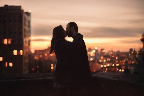 Young couple kissing while standing on the urban rooftop in the evening