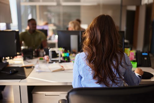Rear view of a female graphic designer working on desktop PC in the office.