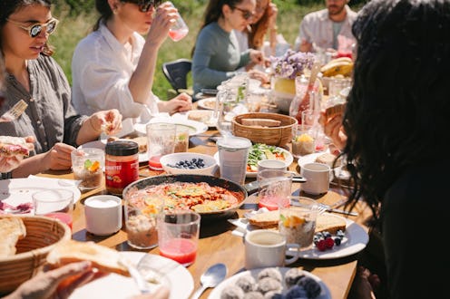 Group of young people enjoying vegan brunch outdoors on a sunny day.