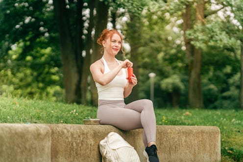 Woman having a red smoothie with her lunch in the park. Part of a phot series of a woman spending a ...