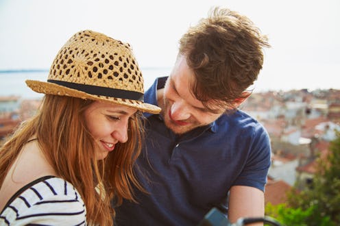 Young man looking at her girlfriend with love. Standing over the old city.