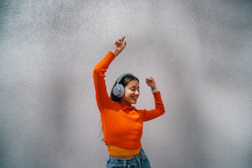 Happy young woman dancing in front of urban concrete wall. Happiness and vitality concept.