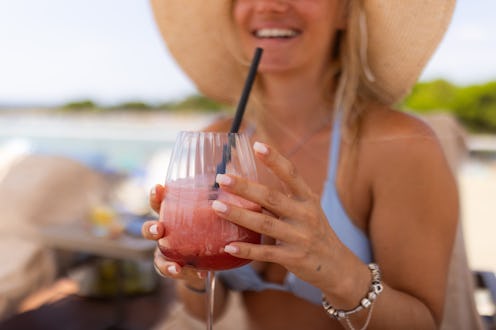 Close-up of happy woman holding cocktail during summer day by the pool