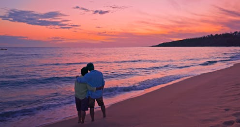 Silhouette of back view asian elderly couple enjoying sunset over the sea
