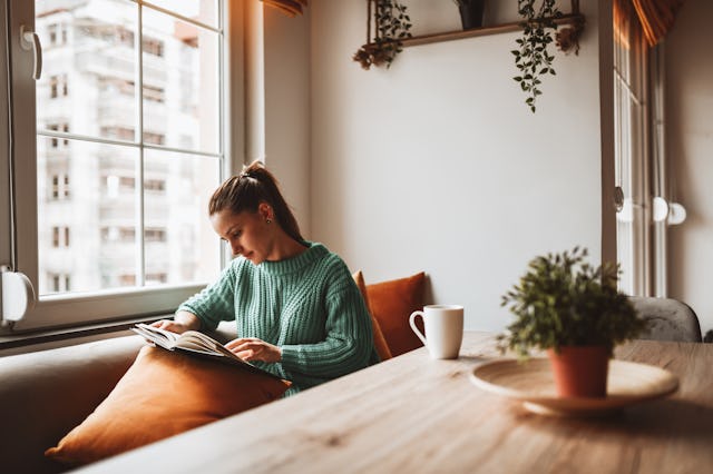 Female Looking At Old Photo Album In Home Kitchen