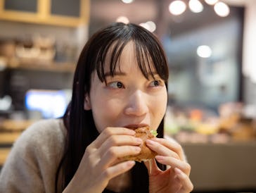 Woman eating hamburger for lunch in restaurant